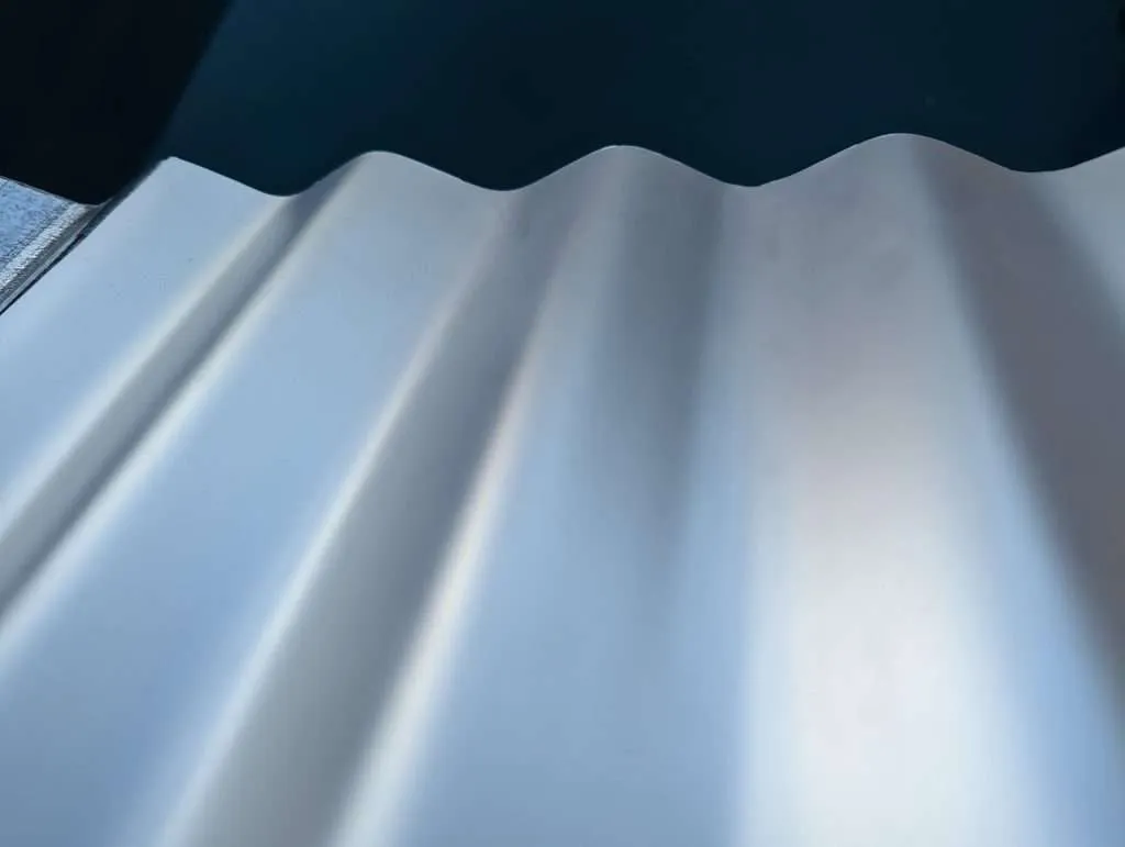 Radiative cooling reflective membrane on corrugated metal roofing.